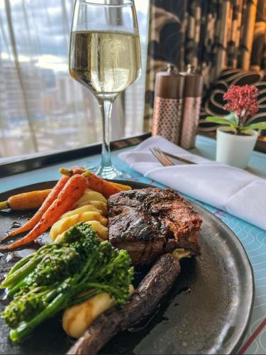 a plate of steak and vegetables with a glass of wine at Crowne Plaza Manchester City Centre by IHG in Manchester