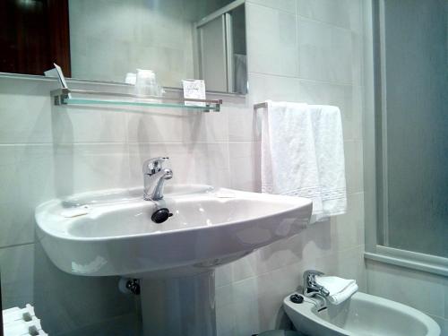 a white bathroom with a sink and a toilet at Hotel Delicias in Zaragoza