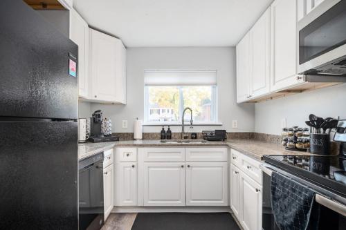 a kitchen with white cabinets and a black refrigerator at The Traveler's Retreat, 5 mins to airport and 15 mins to downtown in Atlanta
