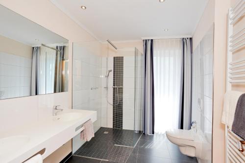 a white bathroom with a sink and a toilet at Hotel Hochheide in Willingen