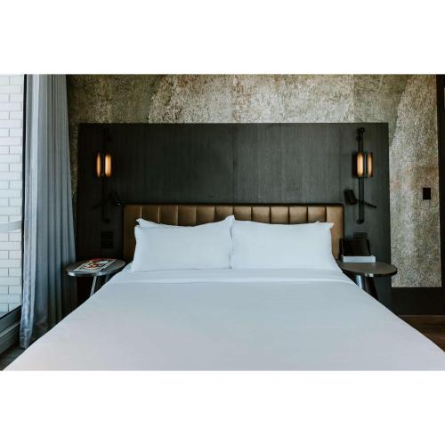 a large white bed in a room with two tables at The Motley Hotel Richmond, Tapestry Collection by Hilton in Melbourne