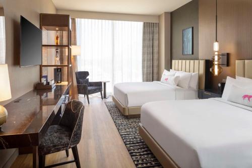 a hotel room with two beds and a desk at Caesars Republic Scottsdale, a Hilton Hotel in Scottsdale