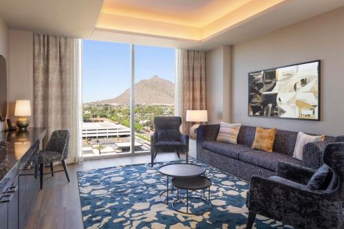 a living room with a couch and a large window at Caesars Republic Scottsdale, a Hilton Hotel in Scottsdale