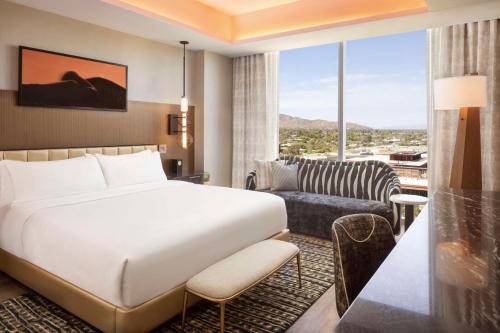 a hotel room with a bed and a large window at Caesars Republic Scottsdale, a Hilton Hotel in Scottsdale
