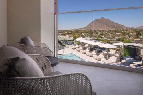 a hotel room with chairs and a view of a pool at Caesars Republic Scottsdale, a Hilton Hotel in Scottsdale