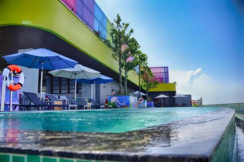 a swimming pool with chairs and umbrellas next to a building at FLAMING0 Ibiza Hải Tiến Resort in Thanh Hóa