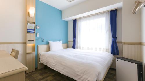 a bedroom with a white bed and a window at Toyoko Inn Kurashiki-eki Minami-guchi in Kurashiki