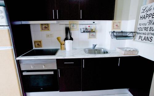 a kitchen with black cabinets and a sink at Hernando Sea Front Optic Fiber Internet Apartment in Calpe