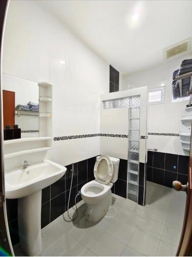 a bathroom with a toilet and a sink at BaanRatsitornHomestay in Langu