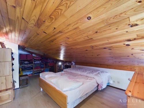 un lit dans une chambre avec un plafond en bois dans l'établissement Studio avec mezzanine pour 4 pers, proche commerces et remontées - FR-1-398-677, à Montvalezan