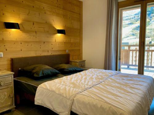 - une chambre avec un lit et un mur en bois dans l'établissement Appartement neuf, lumineux, à 250m des pistes, animaux admis - FR-1-811-4, à Les Deux Alpes