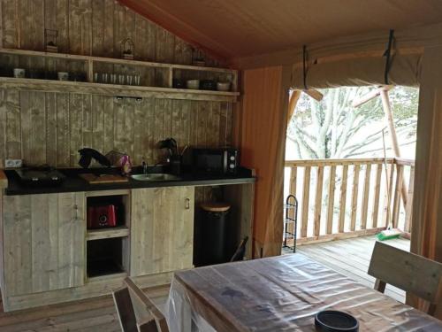 - une cuisine avec des placards en bois et une table dans une pièce dans l'établissement Cabane Trappeur Lodge avec Jacuzzi et Ferme Pédagogique - FR-1-410-458, à Cérans-Foulletourte