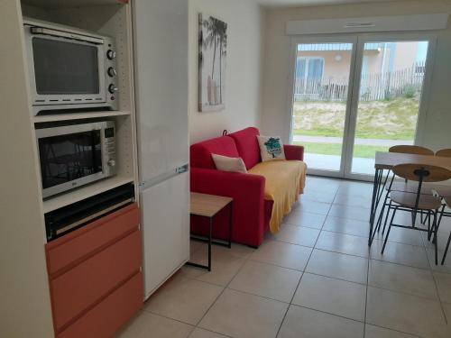 un salon avec un canapé rouge et une télévision dans l'établissement Appartement 4 pers à Mimizan Plage, tout confort entre océan et forêt, terrasse ensoleillée - FR-1-50-148, à Mimizan