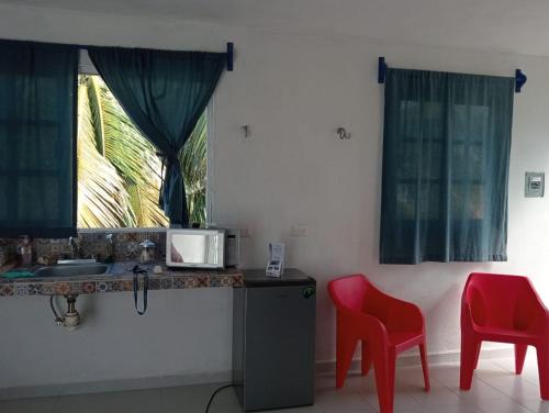 a kitchen with a sink and two red chairs at Happy Sunsets Yucalpetén in Progreso