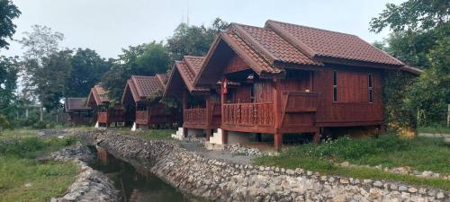 a row of wooden houses next to a river at Starry Night Cottage Resort, Doi lor, Chiangmai in Chiang Mai