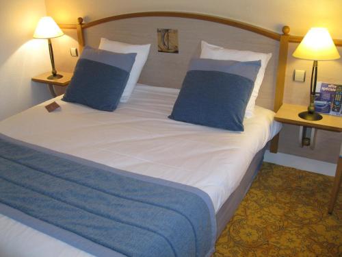 a bed in a hotel room with two blue pillows at Mercure Nevers Pont De Loire in Nevers