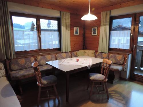 ein Esszimmer mit einem Tisch, Stühlen und Fenstern in der Unterkunft Ferienwohnung Johann Niedermoser in Fieberbrunn