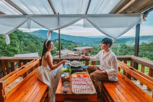 a man and a woman sitting at a table with food at บ้านลิ้นจี่โฮมสเตย์ Baan Lychee homestay in Ban Thung Phan Ha