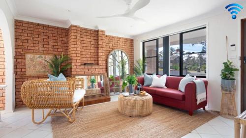 a living room with a red couch and a brick wall at Sunrise Sands in Callala Beach