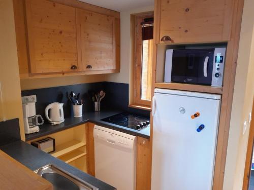 La cuisine est équipée d'un réfrigérateur blanc et d'un four micro-ondes. dans l'établissement Appartement moderne - Proche pistes et commerces - 6 pers. - FR-1-181-2851, à La Plagne Tarentaise