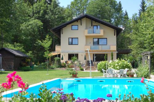 una casa con piscina frente a ella en Haus am Wald, en Faak am See