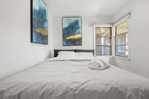 a white bedroom with a large bed with two windows at 3bd Luxury Home, Steps to Calgary DT, River, Hospital in Calgary