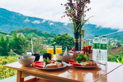 a table topped with plates of food and drinks at บ้านลิ้นจี่โฮมสเตย์ Baan Lychee homestay in Ban Thung Phan Ha