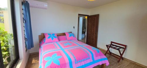 a bedroom with a pink and blue bed and a chair at Villa Ta'u Here in Arue