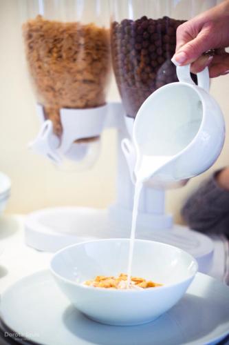 a person pouring milk into a bowl of cereal at Pensjonat Lorien in Szczawno-Zdrój