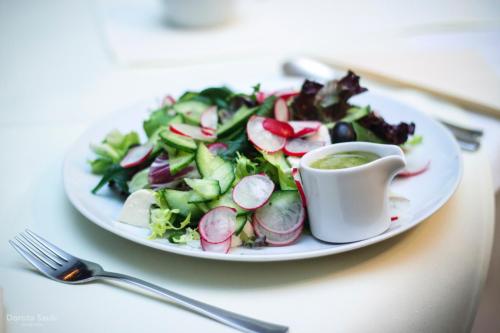 a plate of salad with a cup of green dipping sauce at Pensjonat Lorien in Szczawno-Zdrój