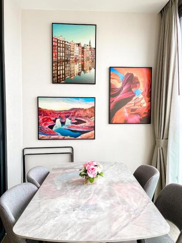 a dining room with a table and four paintings on the wall at The Edge central pattaya in Pattaya Central