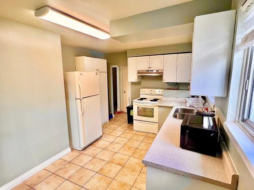cocina con nevera blanca y armarios blancos en Da-7 Room Near Airport, en Brampton