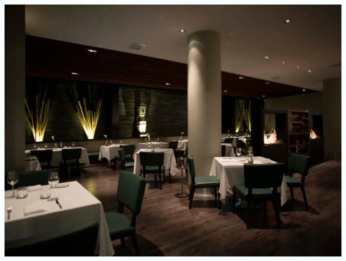 a dining room with white tables and green chairs at Casa Grande Hotel in La Paz