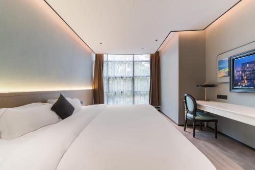 a hotel room with a large bed and a desk at Quanzhou Fengze Square West Street Wanxin Zhige Hotel in Quanzhou