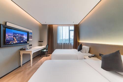 a hotel room with two beds and a desk at Quanzhou Fengze Square West Street Wanxin Zhige Hotel in Quanzhou