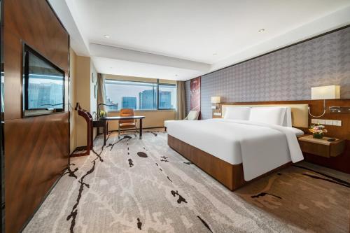 a bedroom with a large white bed and a desk at 佛山南海金融城瑾程酒店 in Nanhai