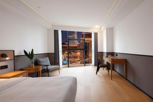 a hotel room with a bed and a desk and a window at Mcsrh Hotel-Chongqing Guanyinqiao in Chongqing