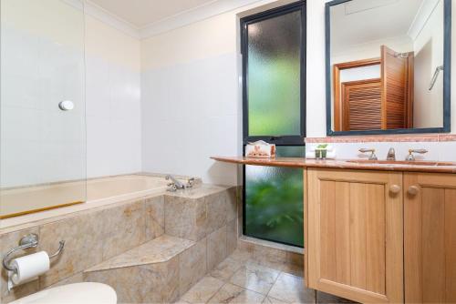 a bathroom with a tub and a sink at The Point Villa 10 in Port Douglas