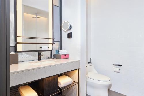 a bathroom with a sink and a toilet and a mirror at Aloft Beijing Huairou in Huairou