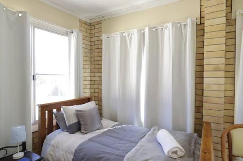 a bedroom with a bed with white curtains and a window at Family Retreat in Central Tenterfield in Tenterfield