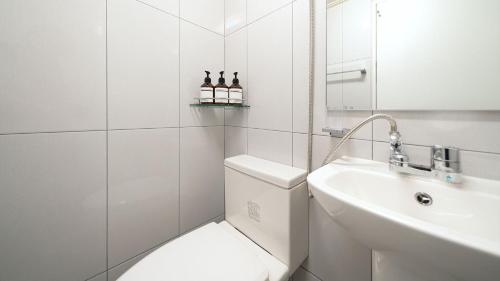 a white bathroom with a toilet and a sink at Hwaseong Refreshing Glamping&Caravan in Hwaseong