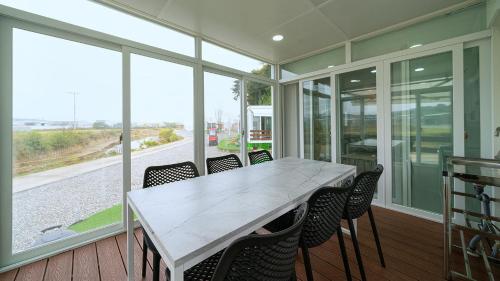 a dining room with a white table and chairs at Hwaseong Refreshing Glamping&Caravan in Hwaseong
