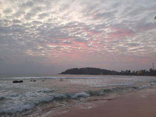 a beach with a cloudy sky and the ocean at One World Mirissa in Mirissa