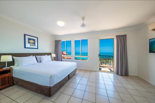 a bedroom with a bed with a view of the ocean at Martinique Whitsunday Resort in Airlie Beach