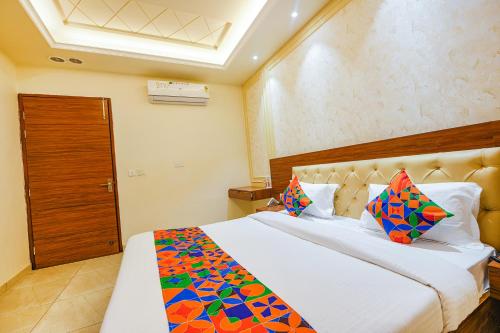 a bedroom with a large white bed with colorful pillows at FabHotel K9 Royal in Ludhiana