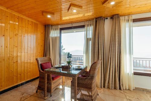 a dining room with a table and chairs and windows at Alaya Stays Lafu Woodscave Room with Attic & Hill views in Shimla