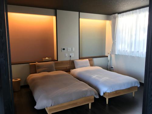 two beds sitting in a room with a mirror at umikaze terrace in Awaji