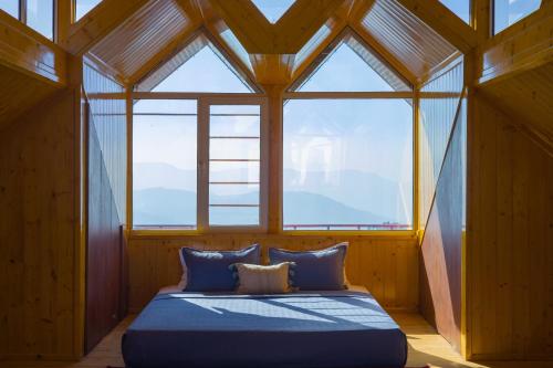 a bedroom with a bed in a room with windows at Alaya Stays Lafu Woodscave Room with Attic & Hill views in Shimla