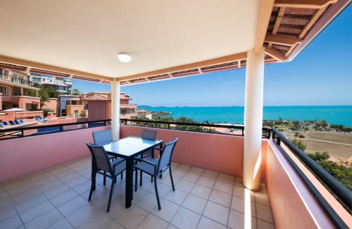 a balcony with a table and chairs overlooking the ocean at Martinique Whitsunday Resort in Airlie Beach