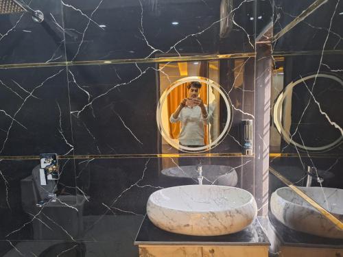 a woman taking a picture of herself in a bathroom mirror at Hotel The Shivraat in Rishīkesh